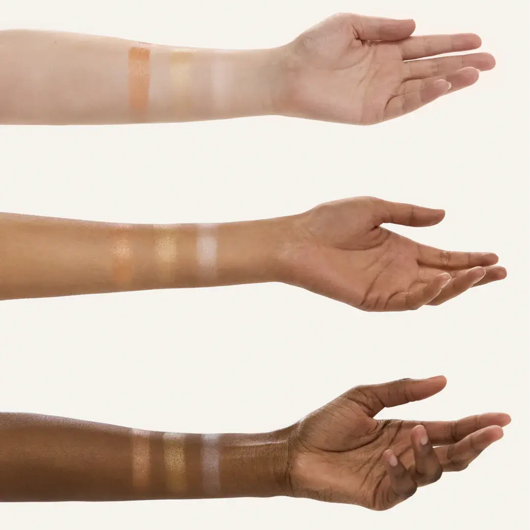 Hands with different skin tones displaying highlighter swatches