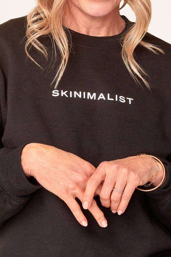 Shop Ember Wellness' line of accessories for the skinimalist. Picture here a woman wears a black 'Skinimalist' crewneck.