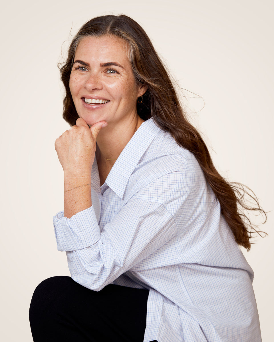 Ember founder Amanda Schuler smiles and looks off-camera. She is wearing a light coloured button up and black pants.