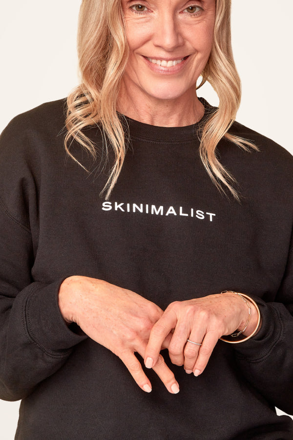 A woman wears Ember's 'Skinimalst' sweatshirt, a cozy black crewneck.